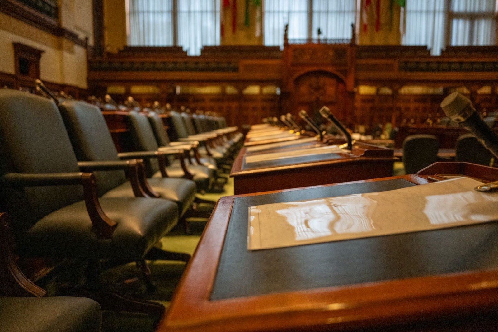 Hémicycle vide d’une assemblée, rangées de pupitres équipés de microphones.